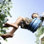 Boy swinging high with joyful abandon, capturing the carefree spirit of childhood