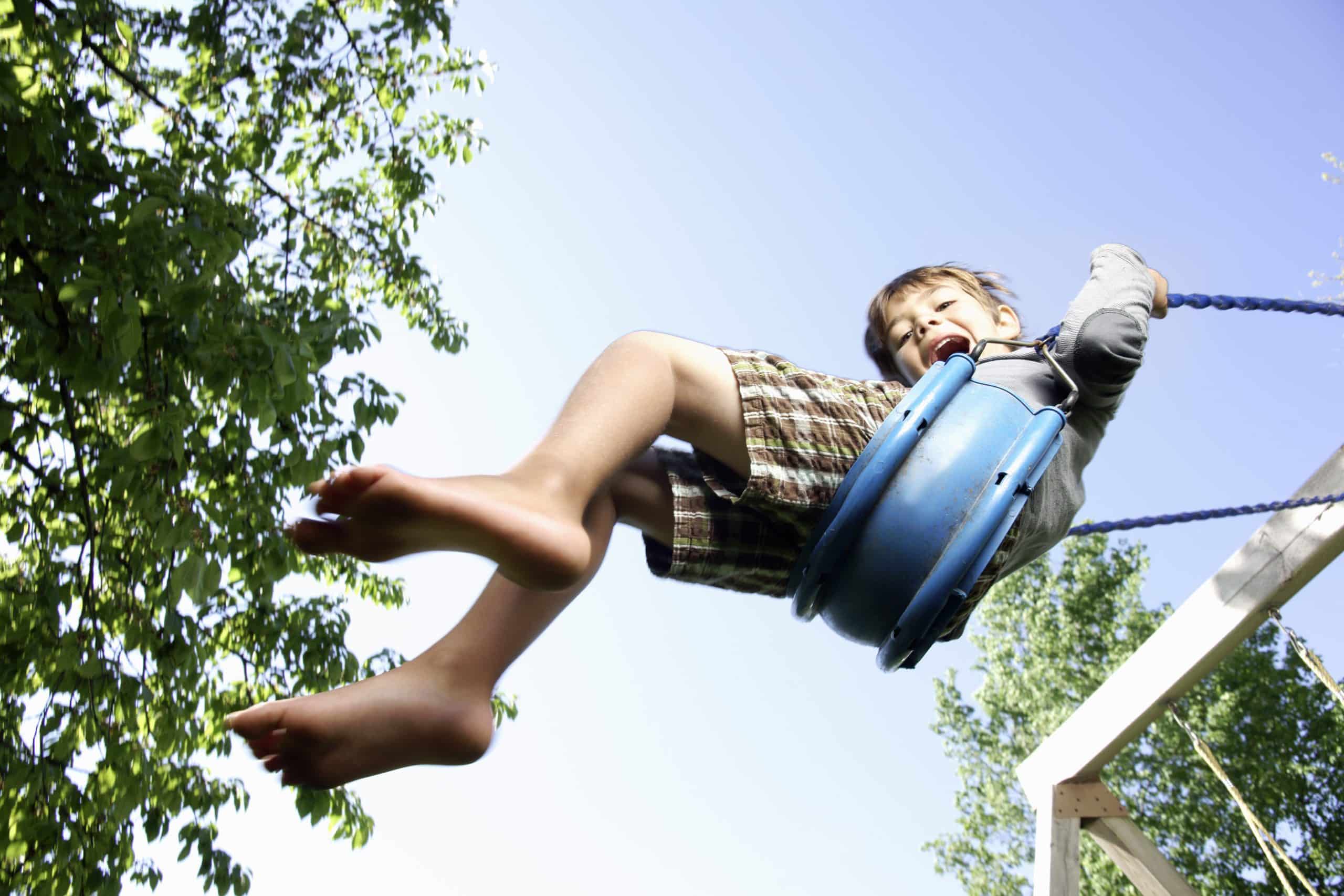 Boy swinging high with joyful abandon, capturing the carefree spirit of childhood