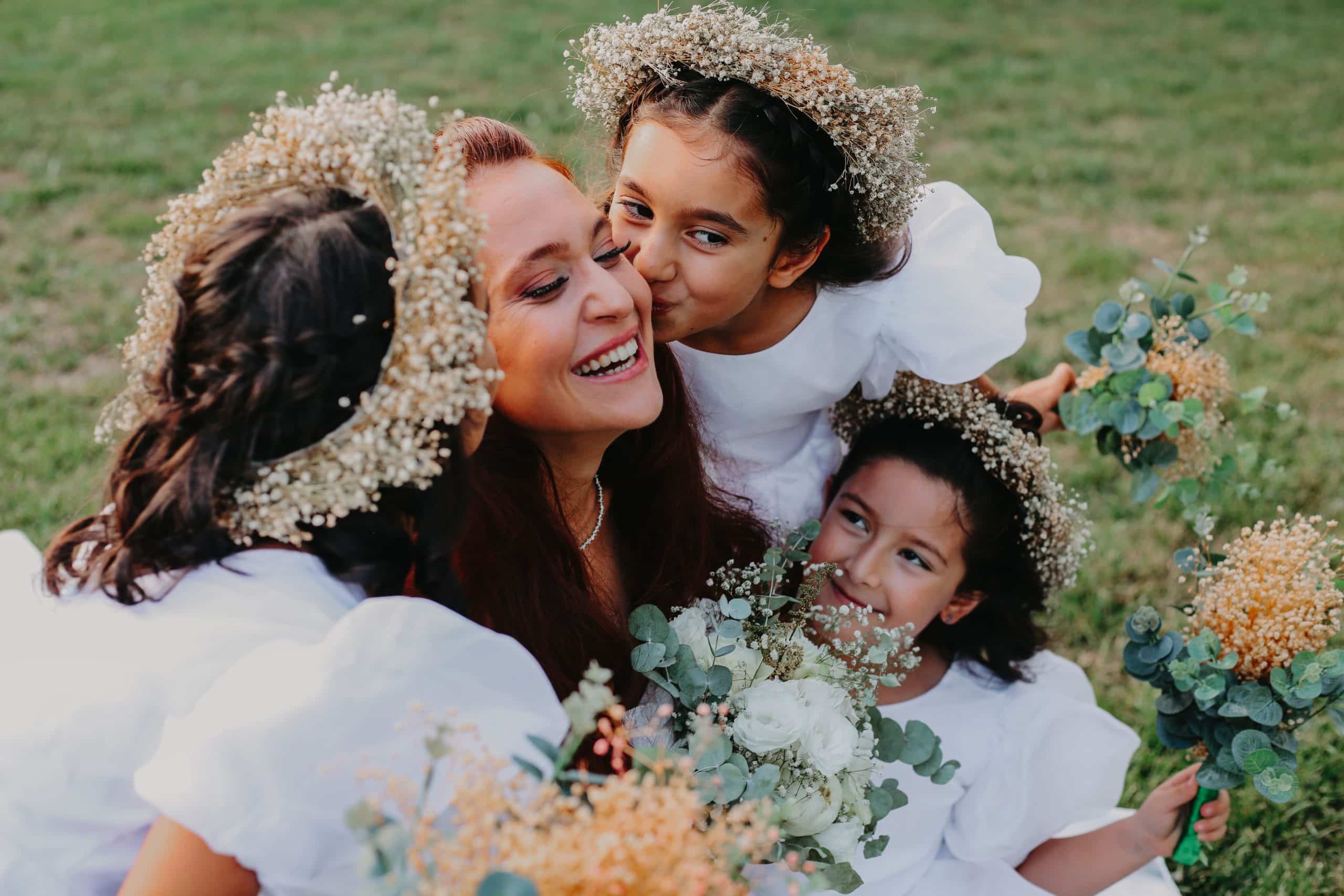 Bride embraced by flower girls in baby's breath crowns, joyful moments worth savoring on your wedding day