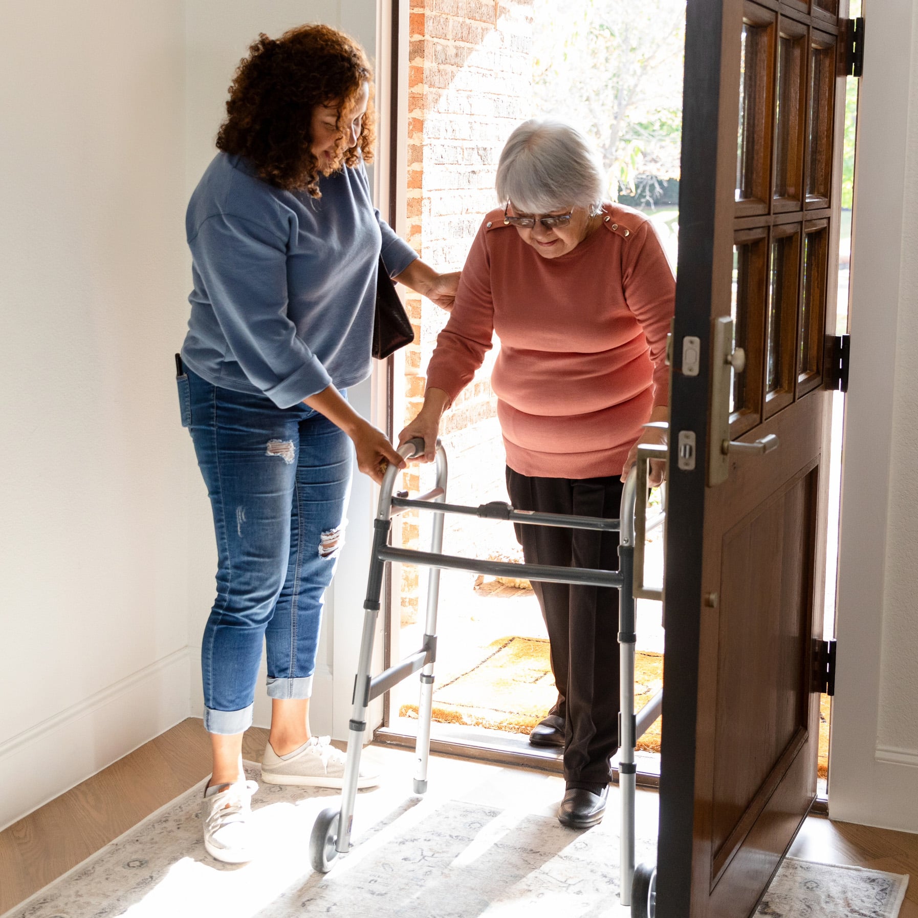 Caregiver assisting senior with walker through doorway, attentive companion care