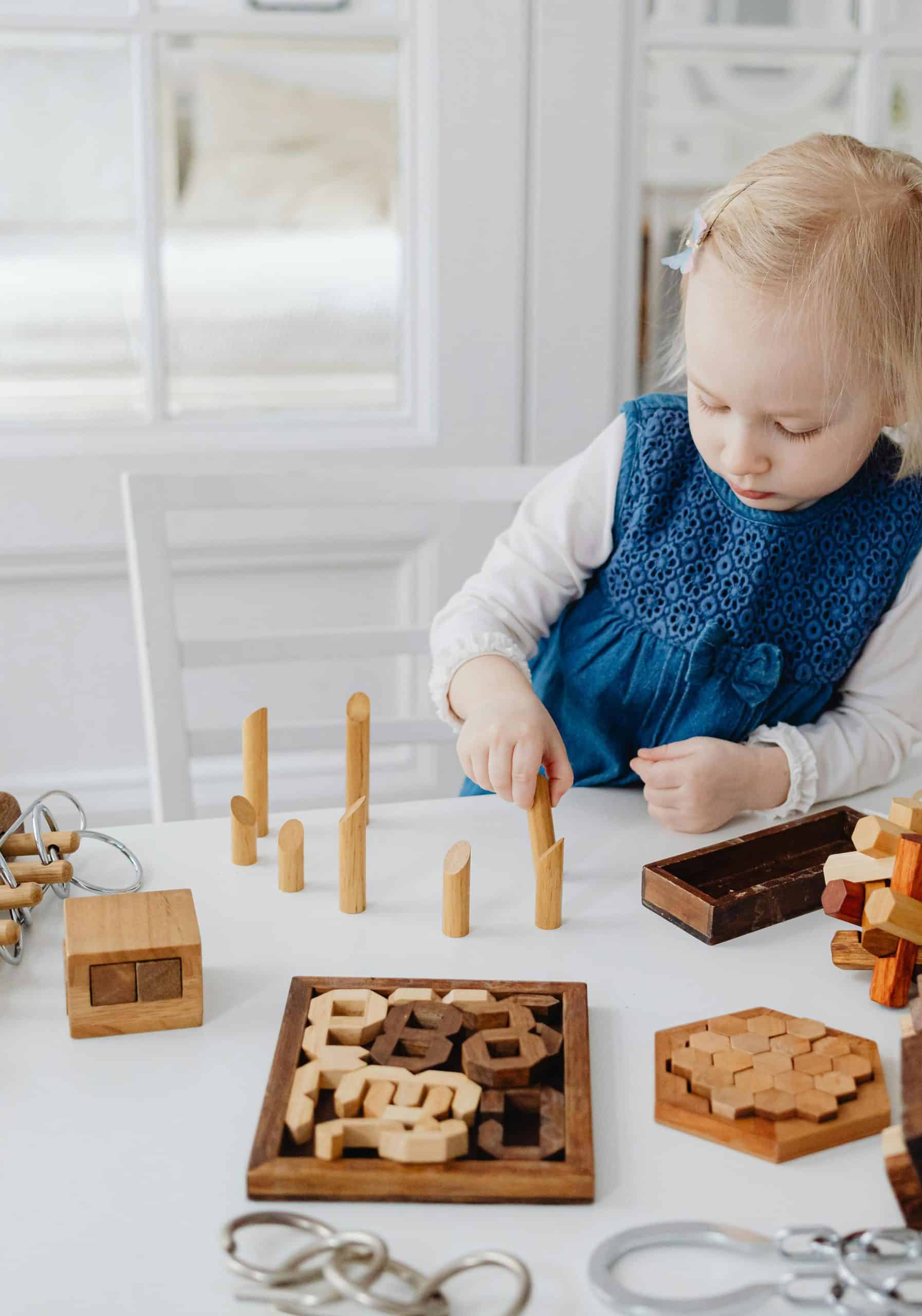 Child engaged in quiet, focused play with wooden puzzles, the kind of calm learning moment skilled childcare supports
