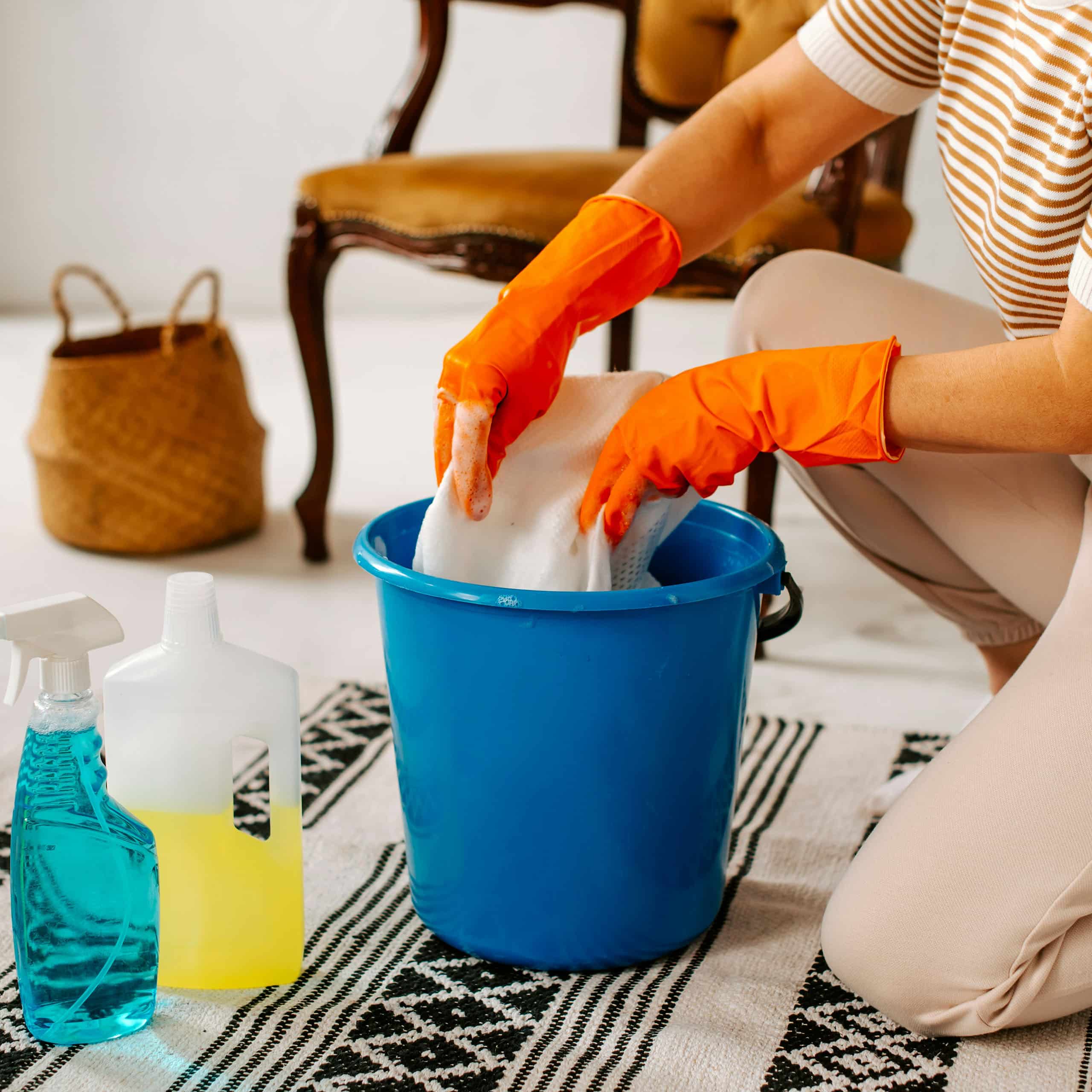 Gloved hands cleaning with bucket and supplies, reliable household assistant support