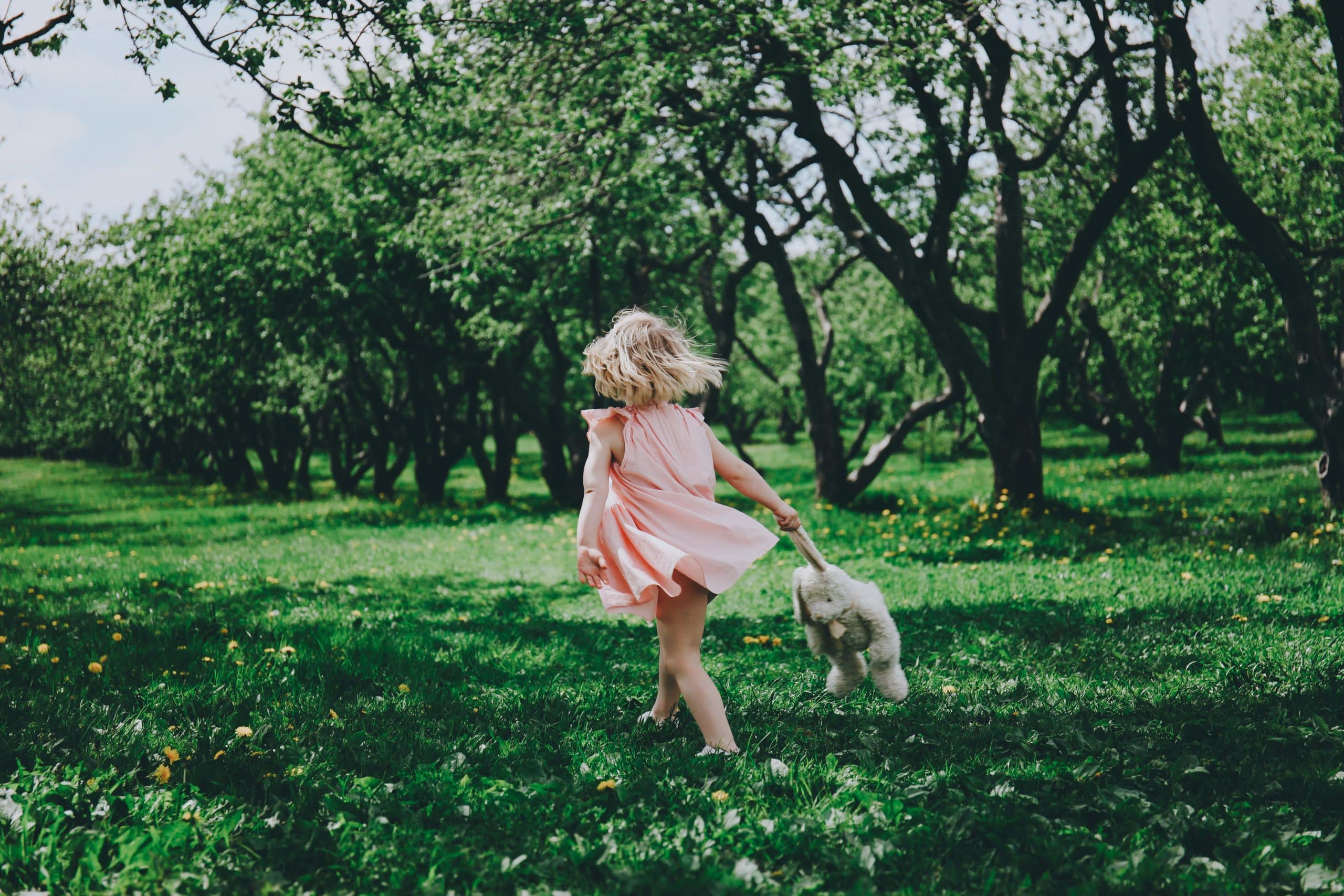 Little girl twirling freely in a sunlit meadow, nurturing childhood through every season