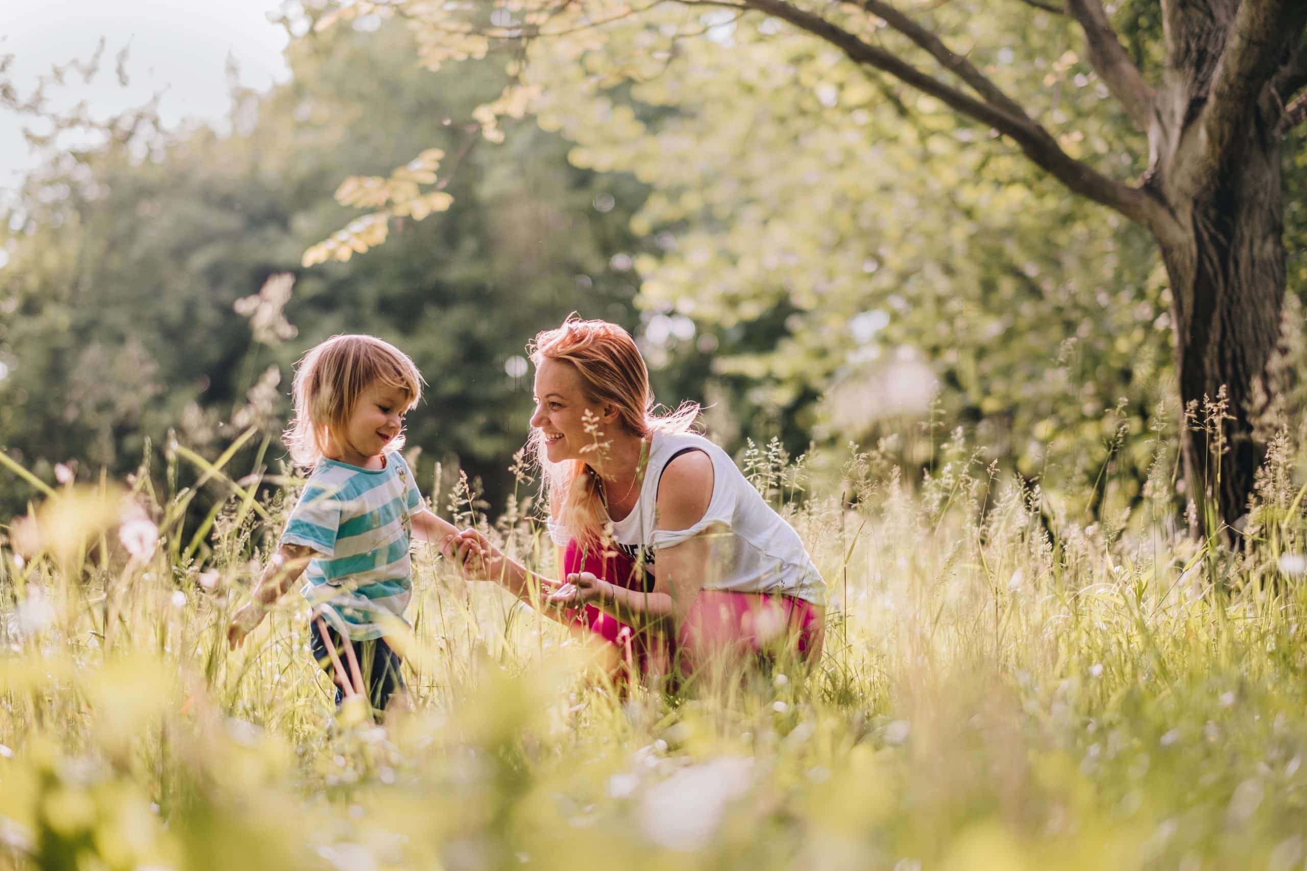 Mom and son laughing together in a sunlit field, sitter care for every stage of life