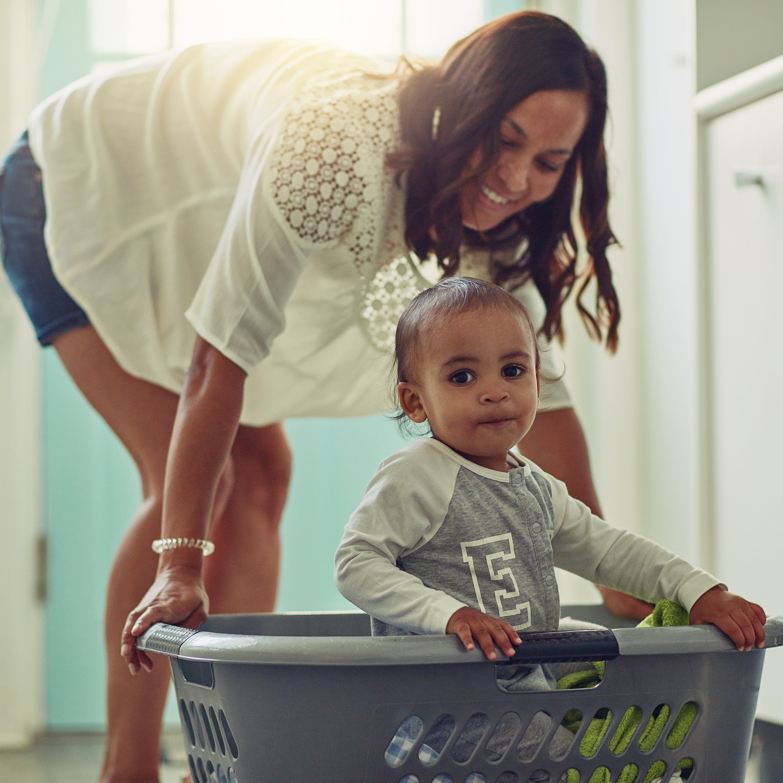 Nanny pushing giggling toddler in a laundry basket, playful advanced nanny care