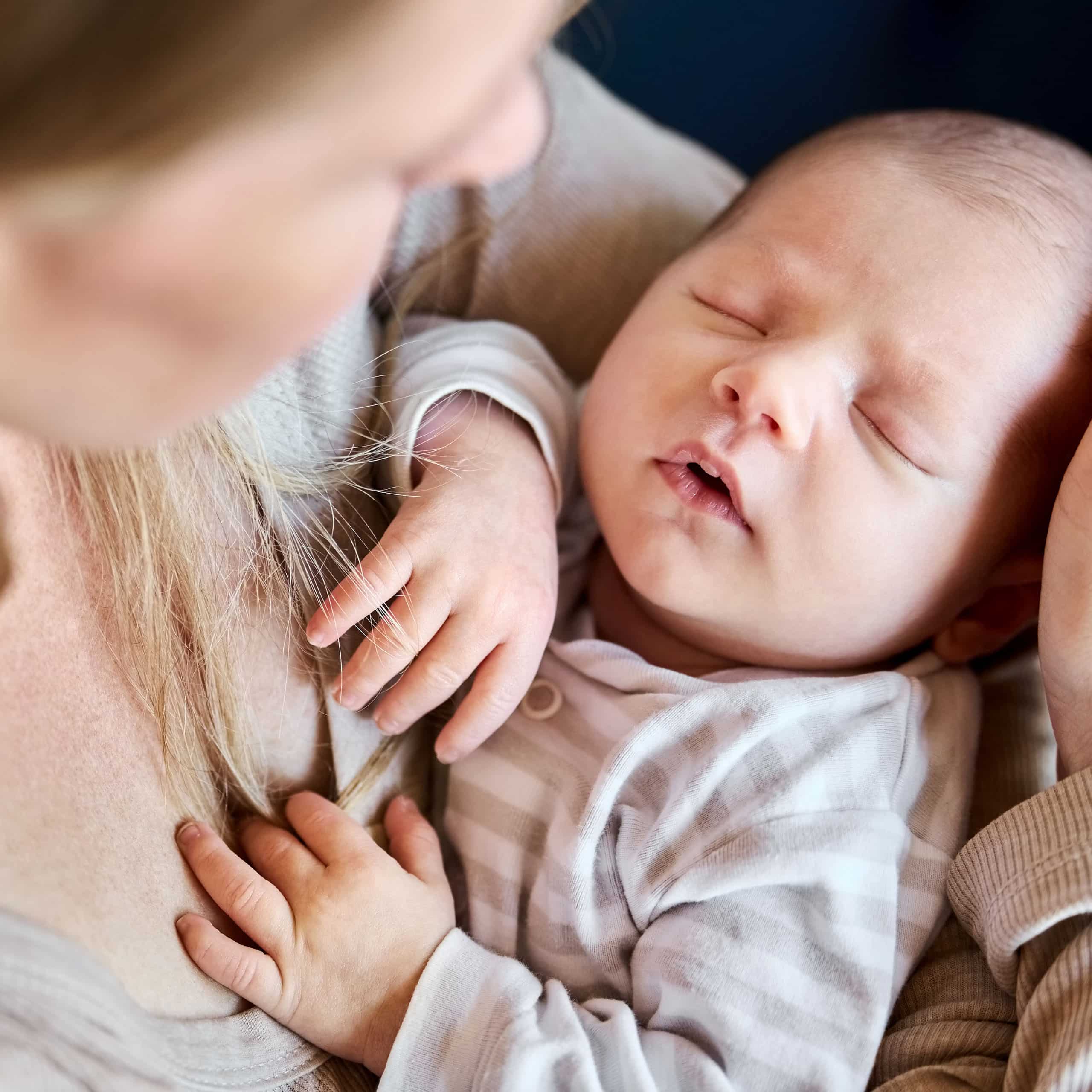Night nanny cradling a sleeping newborn close to her chest, reassuring overnight infant care