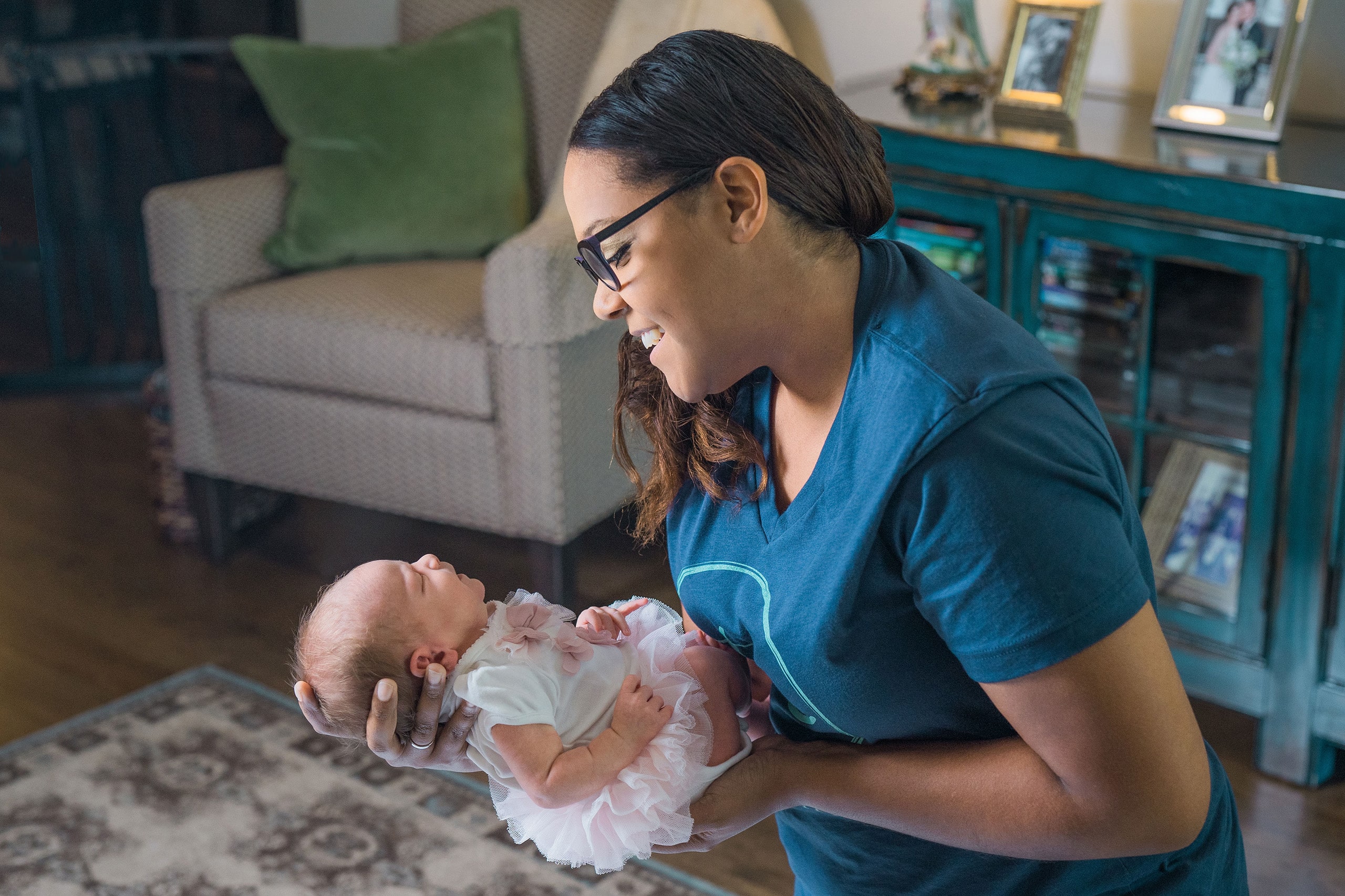 Smiling nanny cradling newborn baby in cozy living room during TC placement