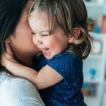 Toddler laughing joyfully while held close by caregiver, the trust that comes with the right fit