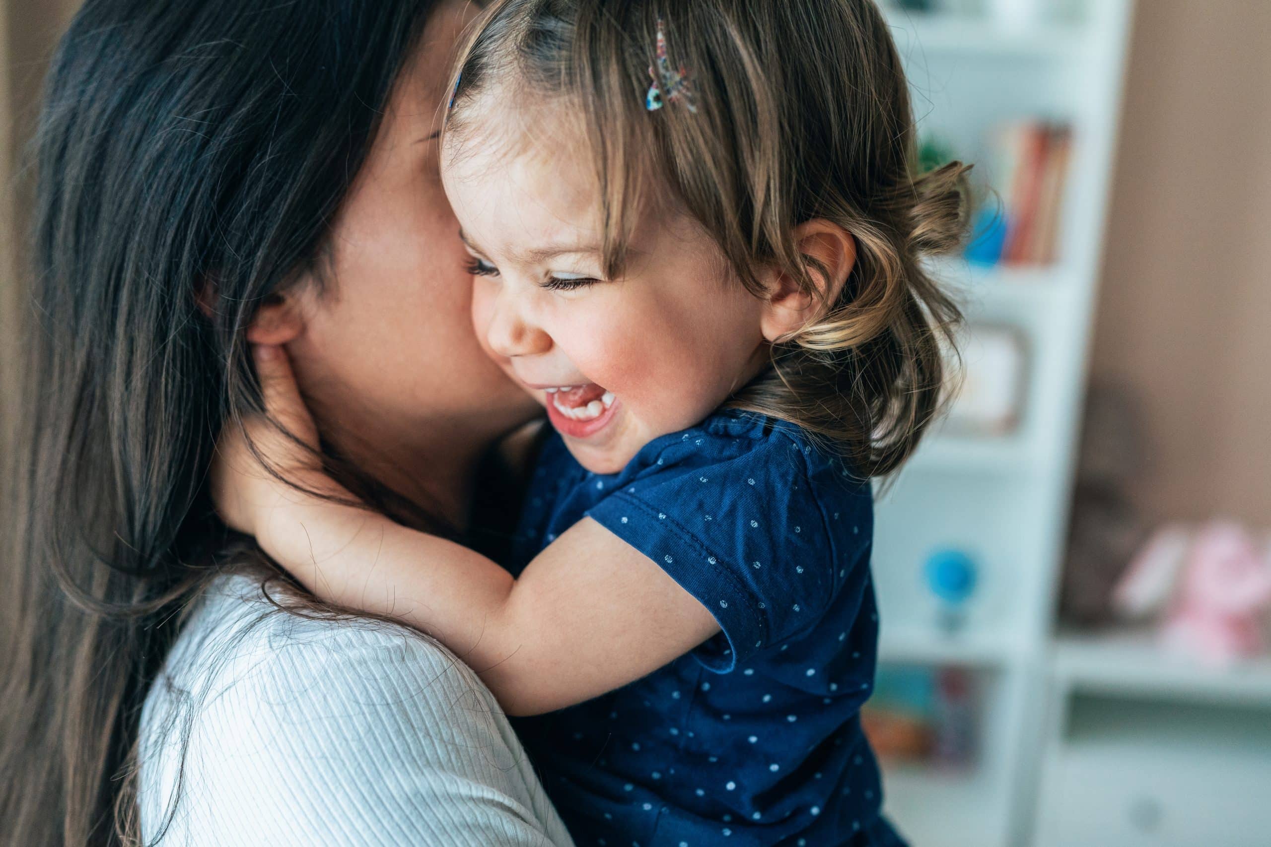 Toddler laughing joyfully while held close by caregiver, the trust that comes with the right fit
