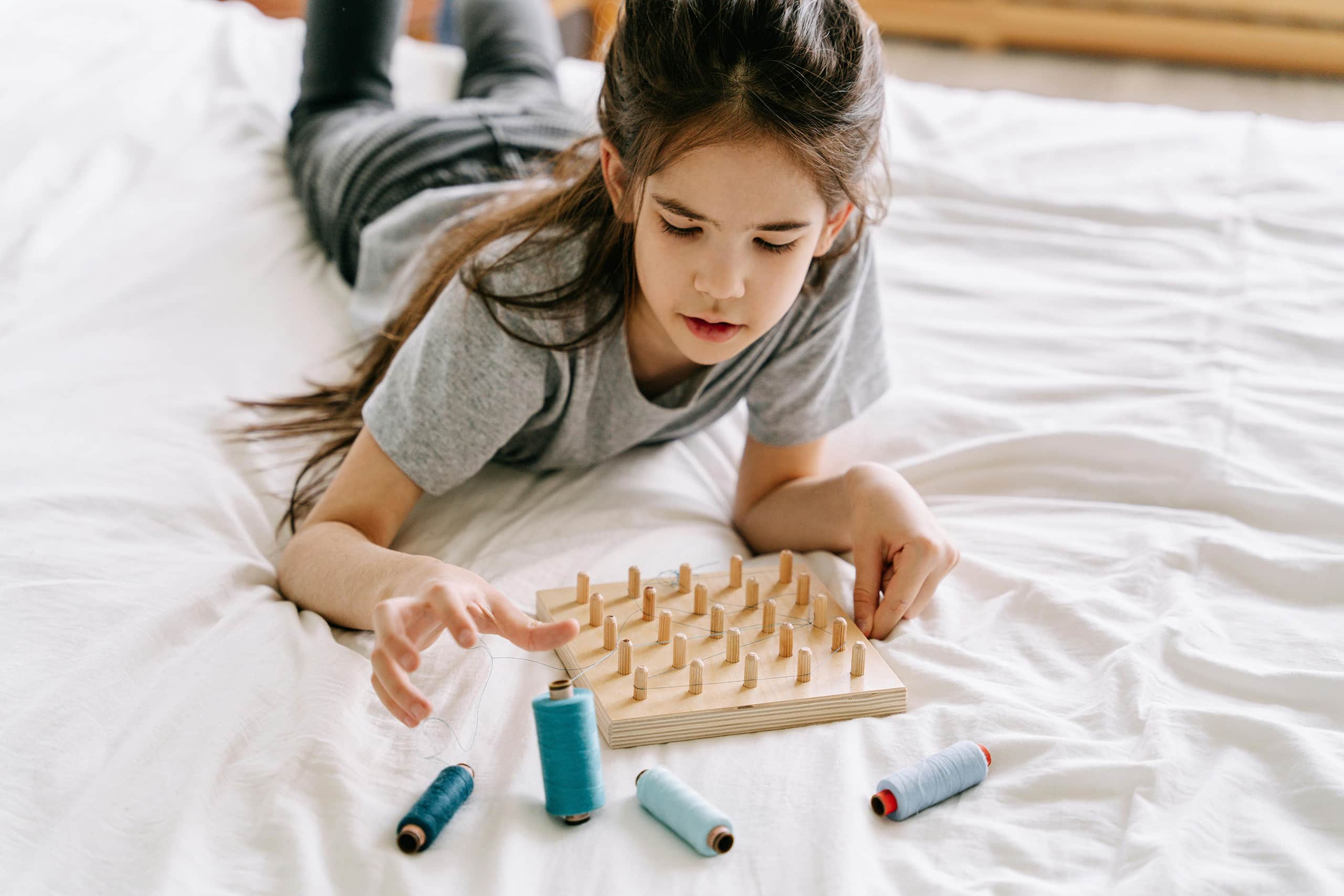 Young girl playing with wooden toys on bed, expert nanny matching success