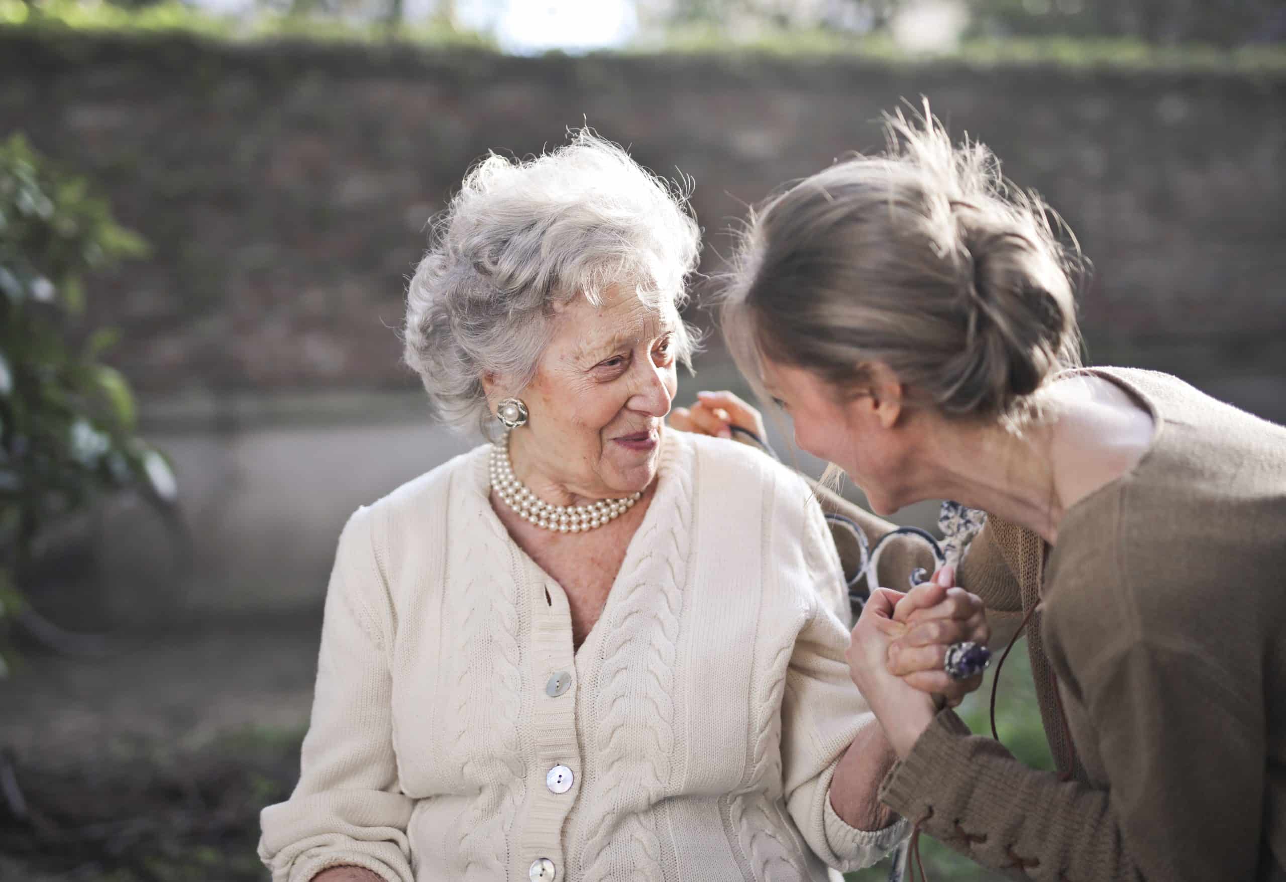 Younger woman and senior sharing an affectionate moment outdoors, the trust behind quality senior care