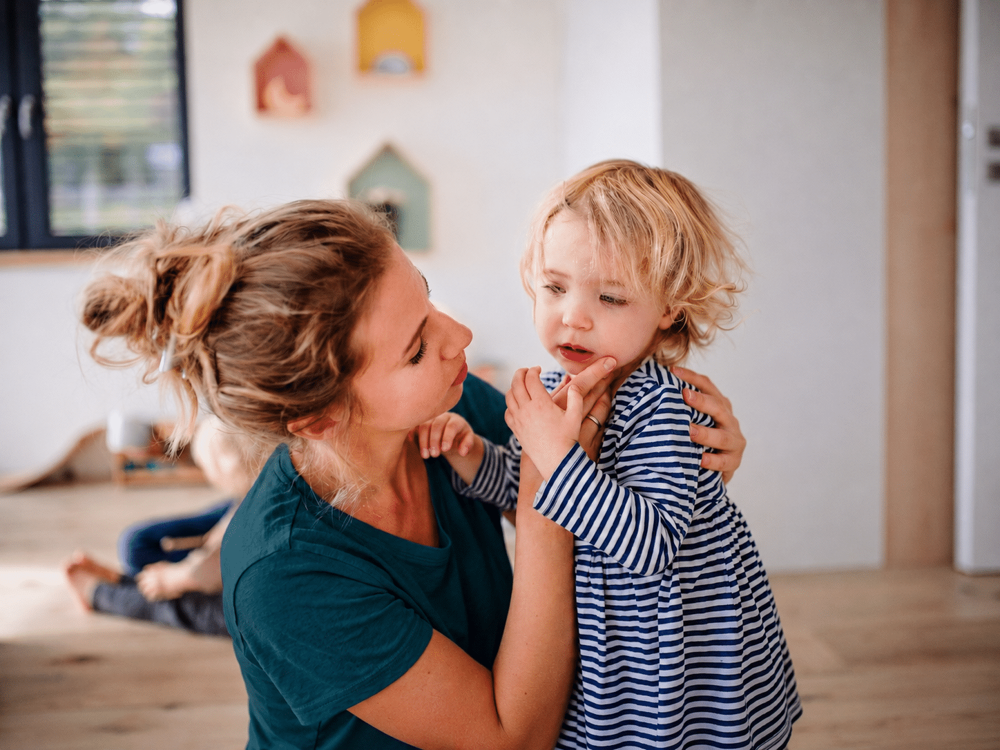 Nanny providing emergency back up child care, comforting a toddler during a last minute care need