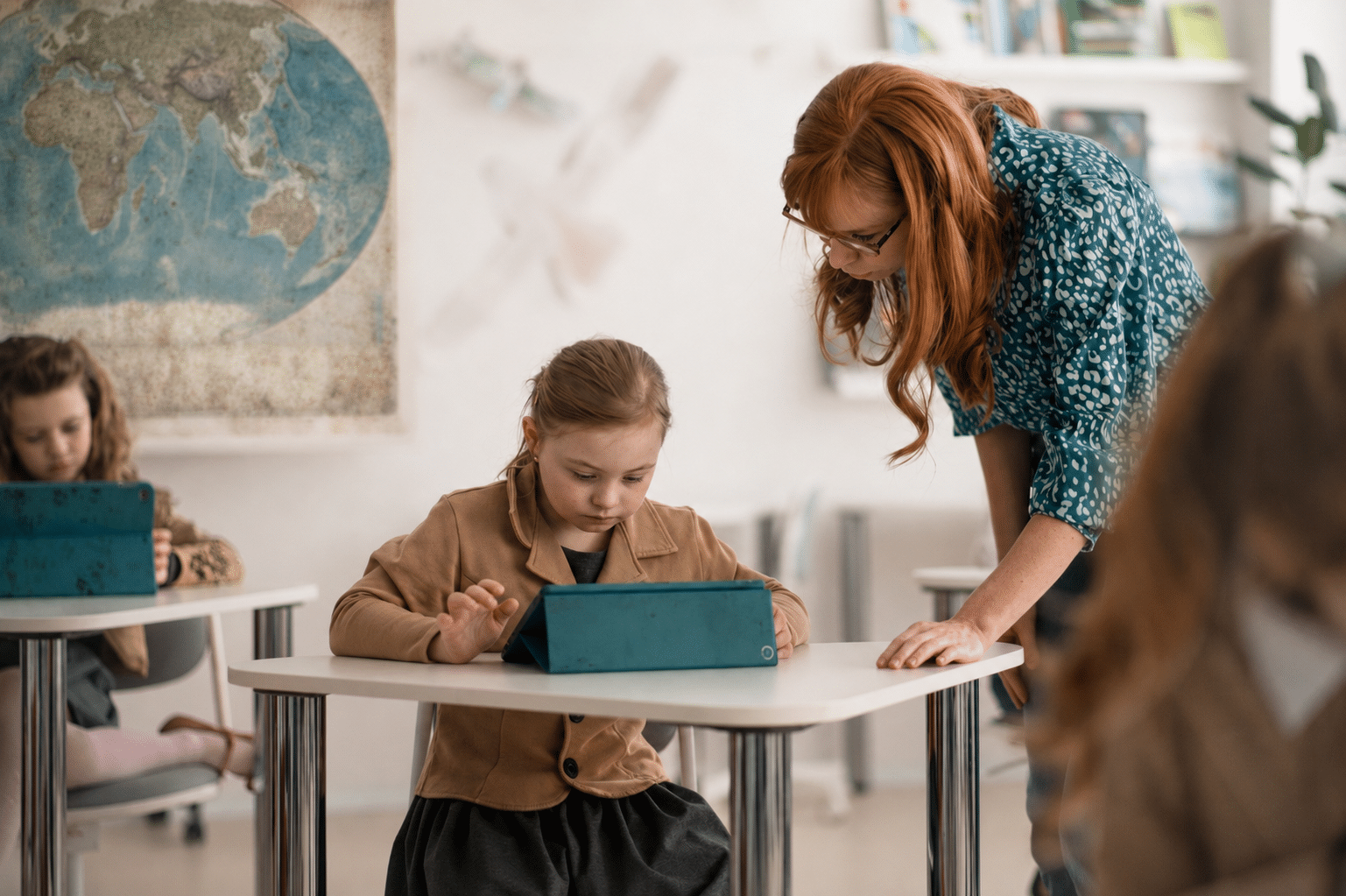 Caregiver providing special needs childcare, checking in with a young student at her desk